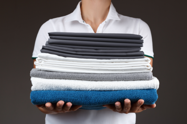 Stack Of Folded Towels And Sheets In Arms 600X400
